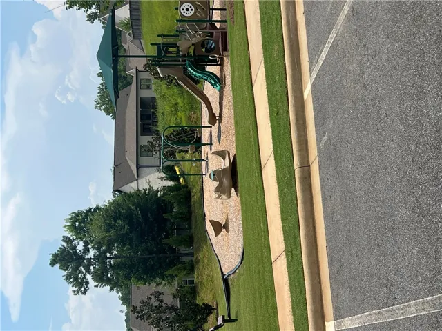 A community playground, perfect for recreation, sits beside a paved parking area.