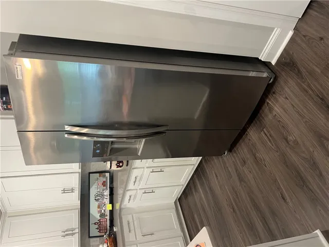 A sleek, modern kitchen boasts a stainless steel refrigerator and elegant wood flooring.