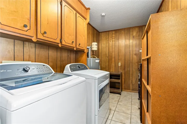 Functional laundry space featuring durable tile flooring and convenient upper cabinetry.