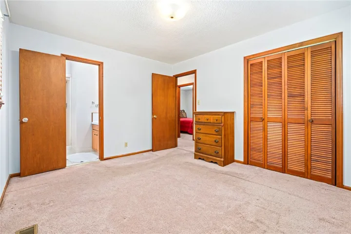 A well-proportioned bedroom features soft carpeting and ample closet space, with access to a private bathroom.