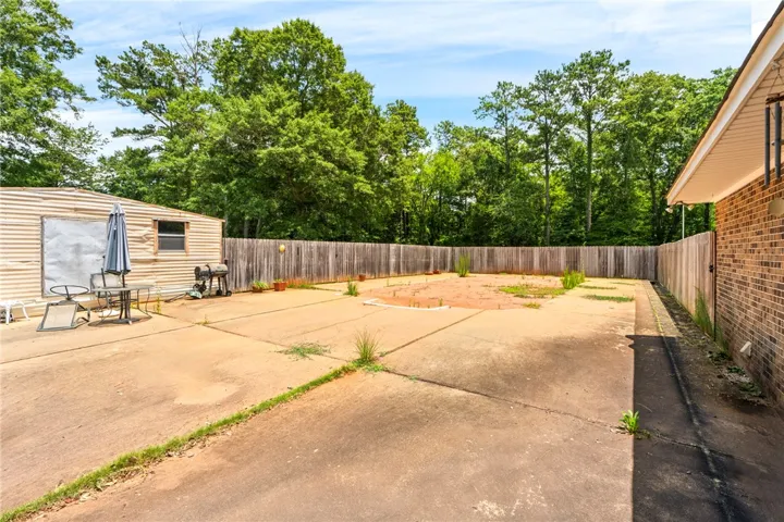 A spacious, enclosed backyard offers a versatile concrete patio area, perfect for outdoor activities.