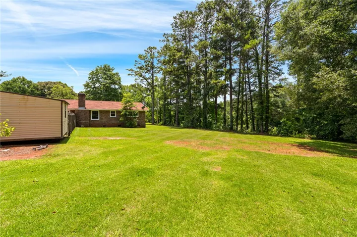 A spacious backyard with mature trees bordering the property line, offering privacy and a verdant setting.
