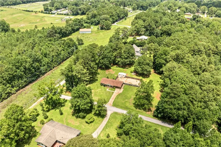 An aerial perspective reveals a serene, wooded estate with a charming residence nestled amidst abundant greenery.