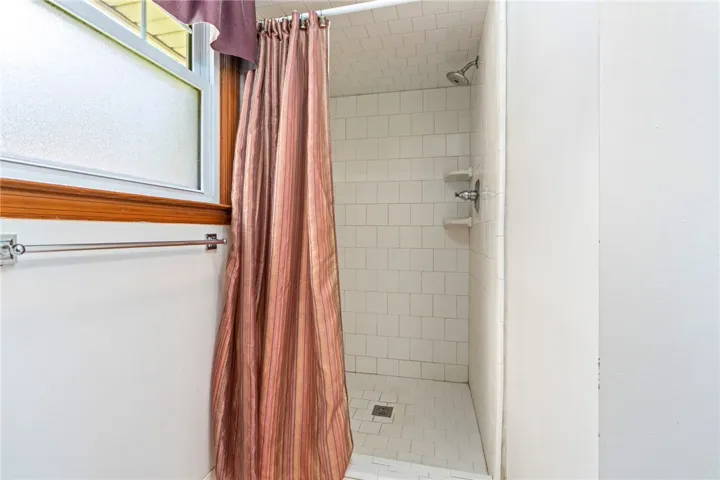 Functional shower with white tile and frosted window for privacy and light.