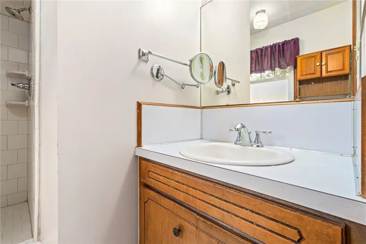 A compact and functional bathroom features a shower with tiled walls and a vanity with a built-in sink.