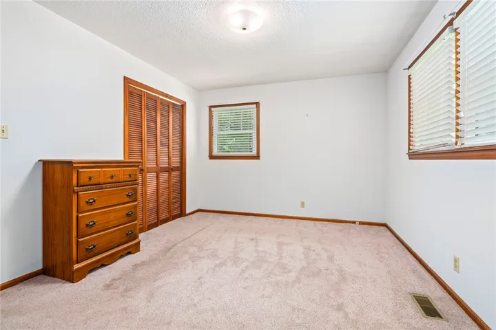 An airy bedroom with plush carpeting features ample natural light through well-appointed windows.