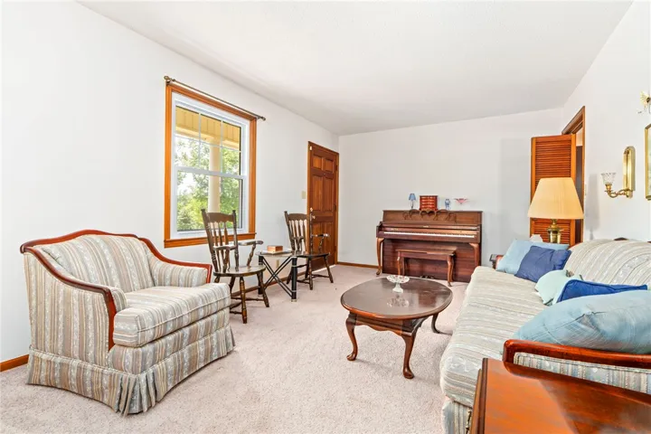 A welcoming living area with ample natural light, soft carpeting, and a classic upright piano.