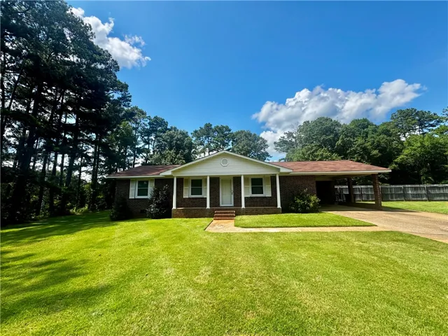 Well-maintained brick home nestled among mature trees offers a private driveway and attached carport.