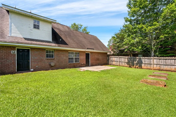 A spacious backyard with mature trees and a privacy fence offers ample outdoor living.