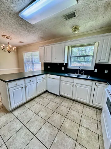 A well-equipped kitchen features ample cabinetry, a double sink, and durable tile flooring.