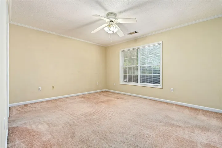 A well-lit bedroom provides a comfortable retreat with a cooling ceiling fan and ample natural illumination.