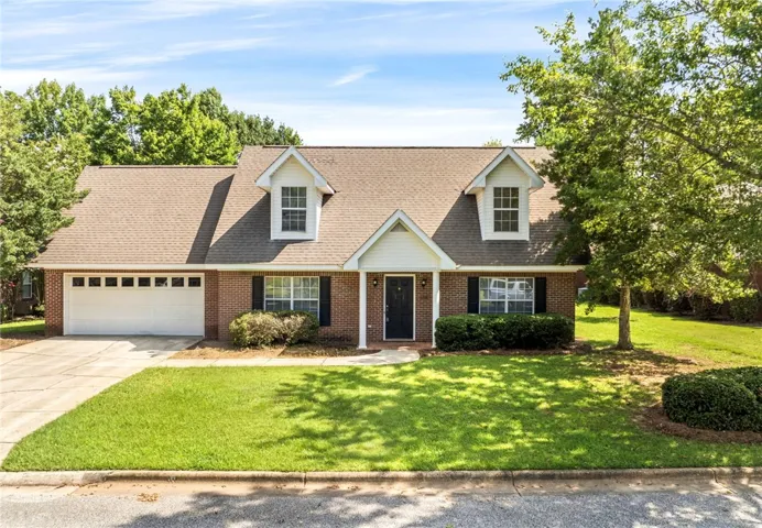 A classic brick exterior, dormer windows, and a manicured lawn create welcoming curb appeal.