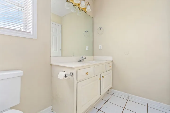A well-lit bathroom with a bright window, a single vanity, and tiled flooring.