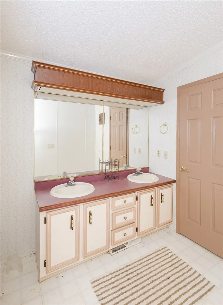 Double vanity with ample counter space and storage cabinetry offers everyday convenience.