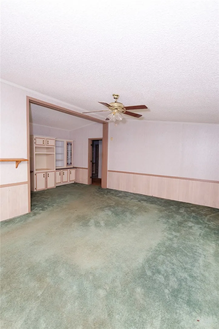 A spacious living room featuring carpet flooring and built-in cabinetry, ready for personalization.