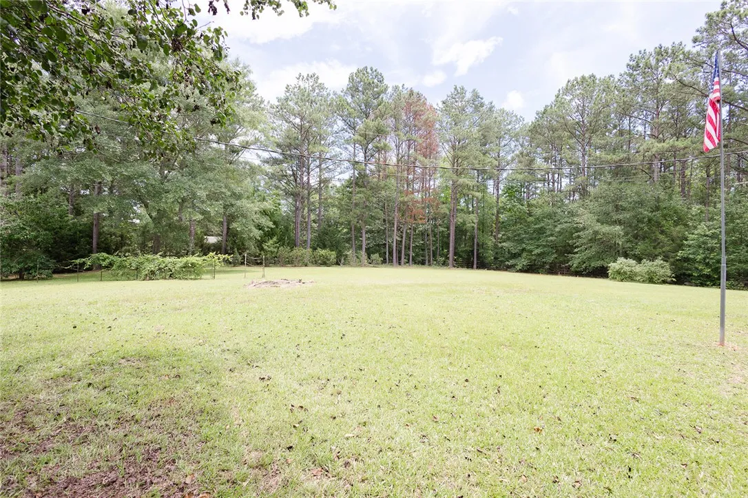 A spacious, verdant yard with mature trees forming a natural border, ready for outdoor enjoyment.