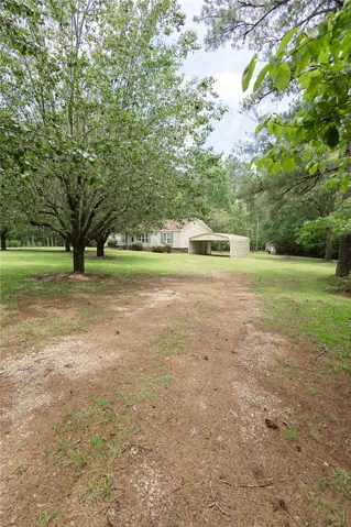 A classic ranch home set amidst a spacious yard with mature trees and a detached carport.