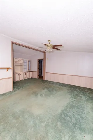 A spacious living room featuring carpet flooring and built-in cabinetry, ready for personalization.