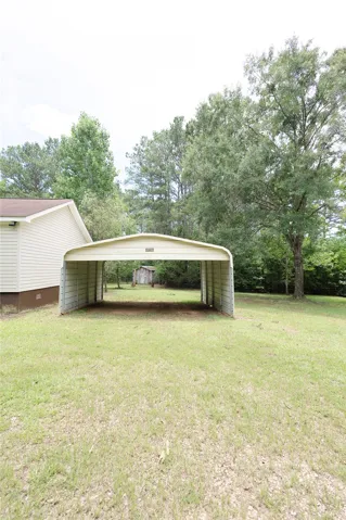 A detached carport offers practical shelter for vehicles, nestled within a verdant setting.