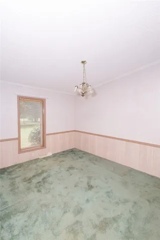 A well-lit room with carpeted flooring and wainscoting offers a versatile space.