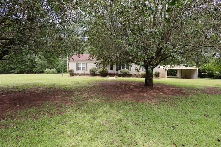 A classic ranch home nestled in a sprawling, verdant yard with mature trees.