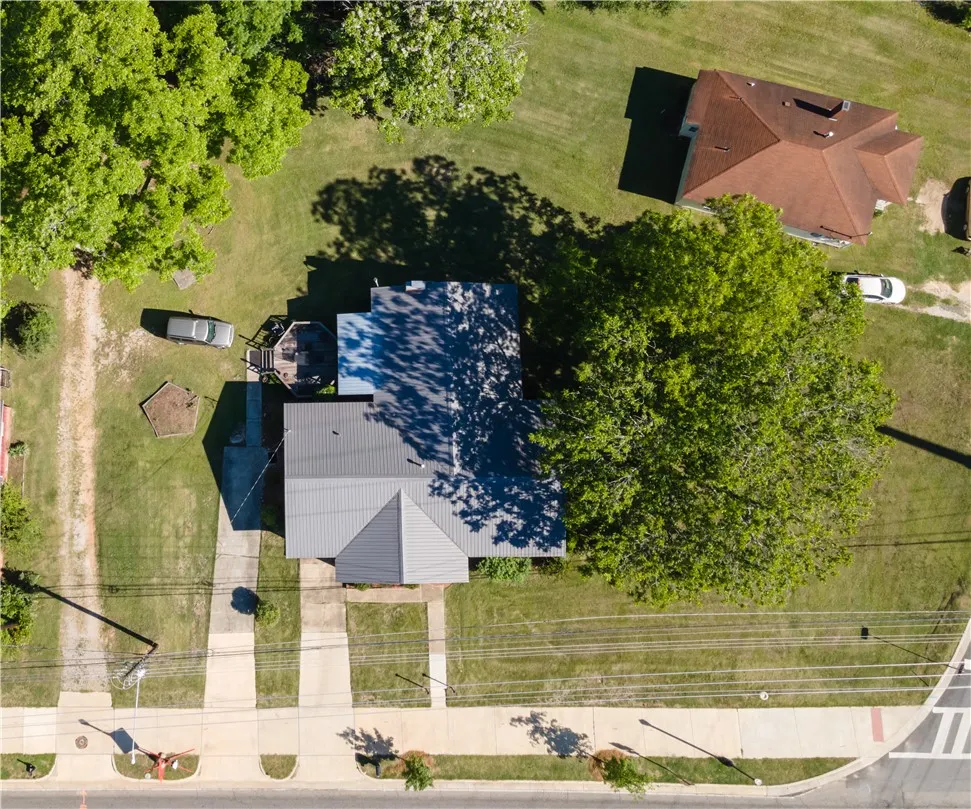 An aerial perspective showcases the property's lot, neighboring structures, and verdant surroundings.