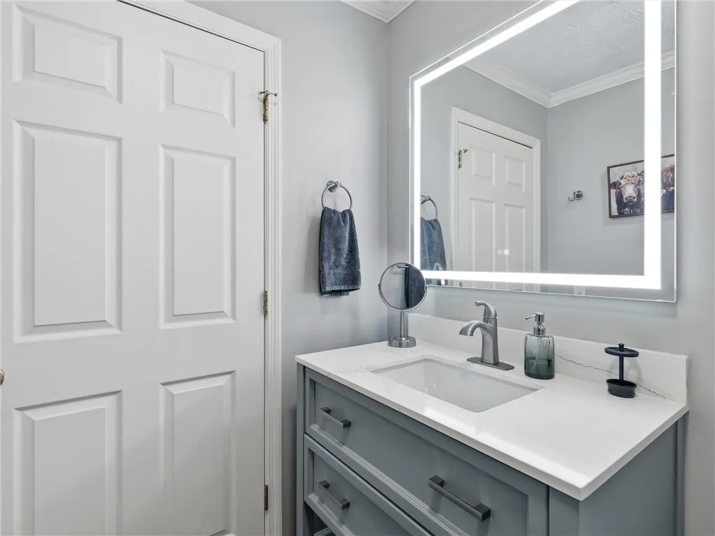 Illuminated mirror and a sleek vanity define this well-appointed bathroom.