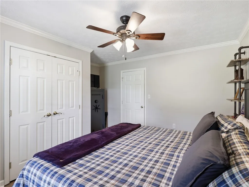 A well-appointed bedroom includes crown molding and a ceiling fan, offering both style and comfort.