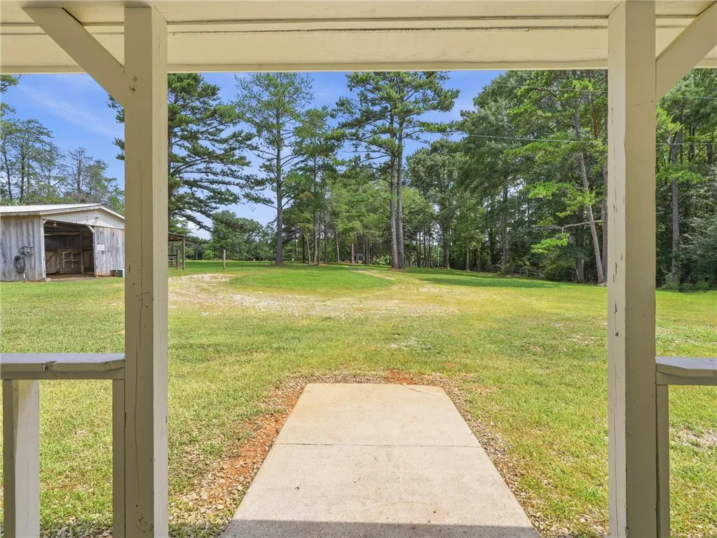 Green pastures and tall pines offer a serene, expansive backdrop to this welcoming outdoor space.