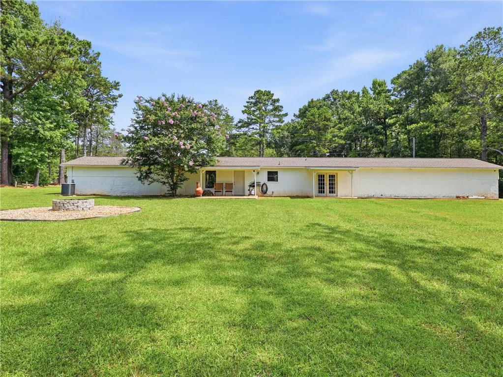 A spacious lawn provides ample outdoor living space with a fire pit and patio, all surrounded by mature trees.
