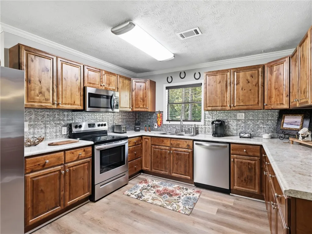 A well-equipped kitchen features wooden cabinetry, bright countertops, and a full suite of stainless steel appliances.