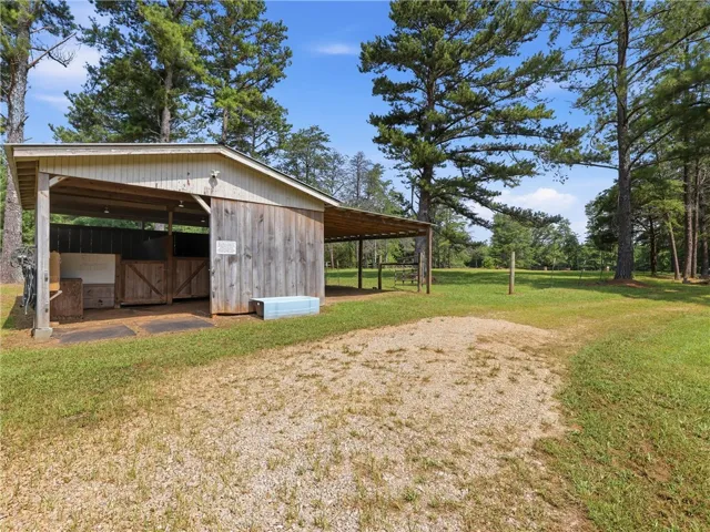 A well-maintained stable structure provides ample shelter in a spacious, verdant setting.