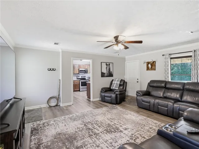 Relax in this comfortable living space, featuring durable wood-look flooring and a peek into the adjacent kitchen.