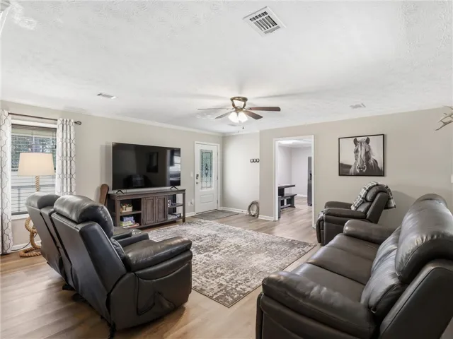 A welcoming living area with wood plank flooring and a decorative ceiling fan above.