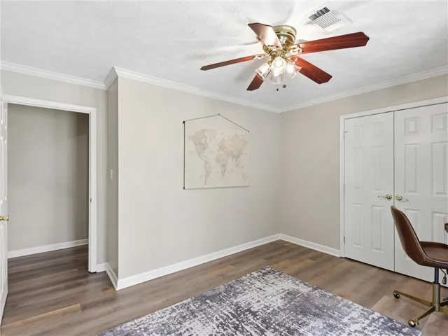 A versatile space features modern wood flooring, crisp crown molding, and a practical ceiling fan.