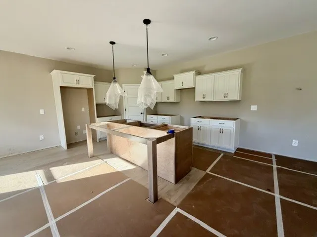 A spacious kitchen with white cabinetry and pendant lighting awaits your personalized touch.