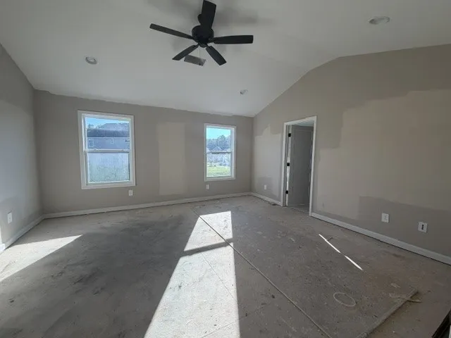 A spacious primary bedroom features soaring vaulted ceilings and abundant natural light from multiple windows.