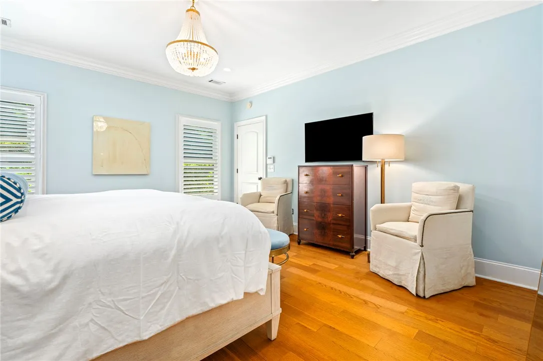 Hardwood floors and a sophisticated chandelier elevate this tranquil sleeping space.