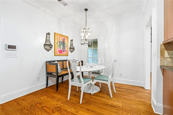 An inviting dining area boasts rich hardwood floors and a contemporary light fixture, perfect for intimate meals.
