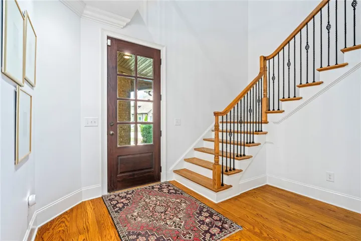 A graceful staircase with intricate wrought iron balusters complements the rich hardwood flooring in this inviting entrance.