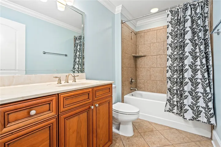 A warm wooden vanity with a cultured marble top complements the light blue walls and tiled shower.