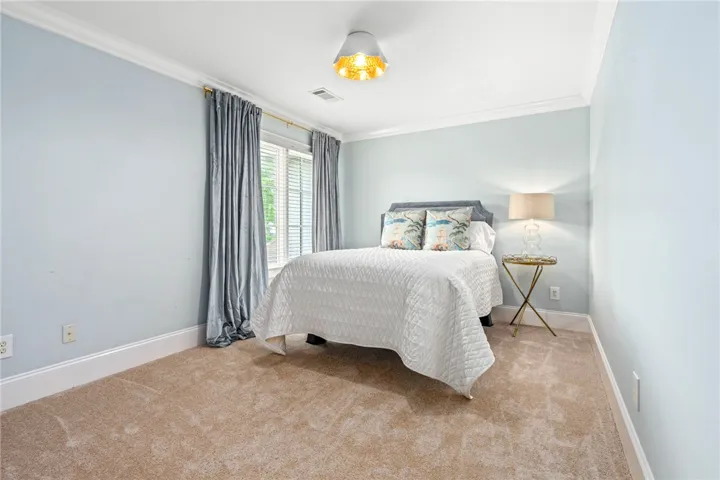 A tranquil bedroom space featuring soft carpeting and crown molding, perfect for rest and relaxation.