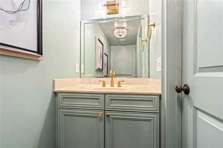 A refined powder room offers a chic vanity with a stone countertop and elegant gold fixtures.