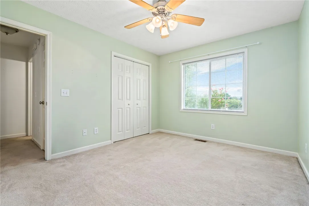 A well-lit bedroom provides comfortable living with carpet flooring and window blinds.