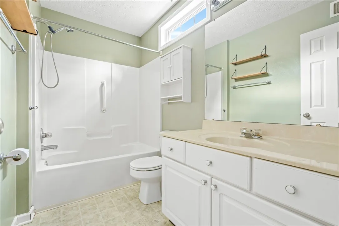 A well-lit primary bathroom features a combination shower and tub, complete with a convenient hand-held showerhead.