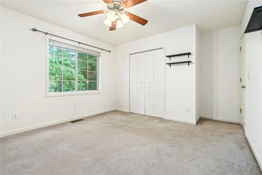 A quiet retreat with a garden view, this bedroom features carpet flooring and a ceiling fan.