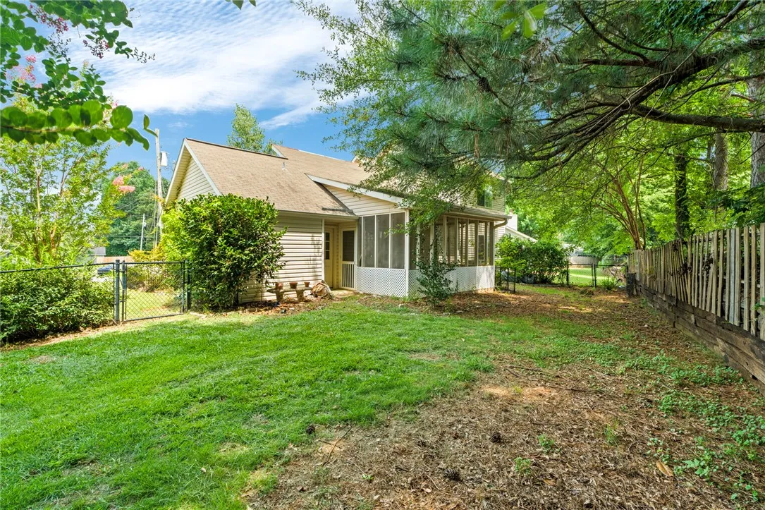 A private, fenced backyard offers a serene escape with mature trees providing ample shade.