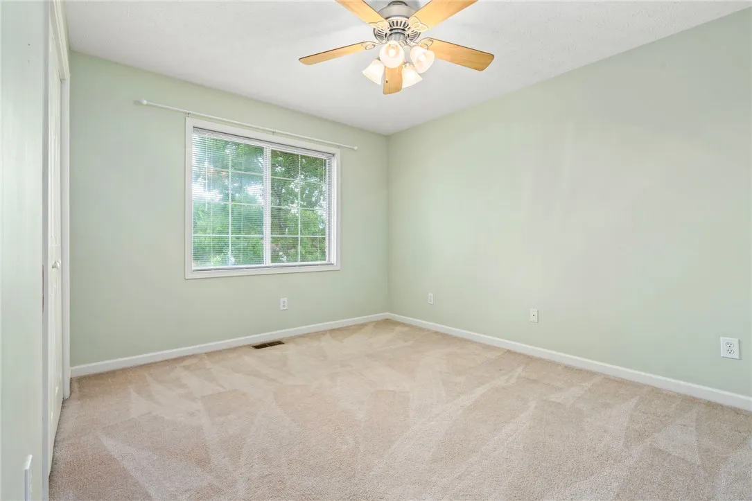 A quiet bedroom offers ample space, a large window, and a ceiling fan for comfort.