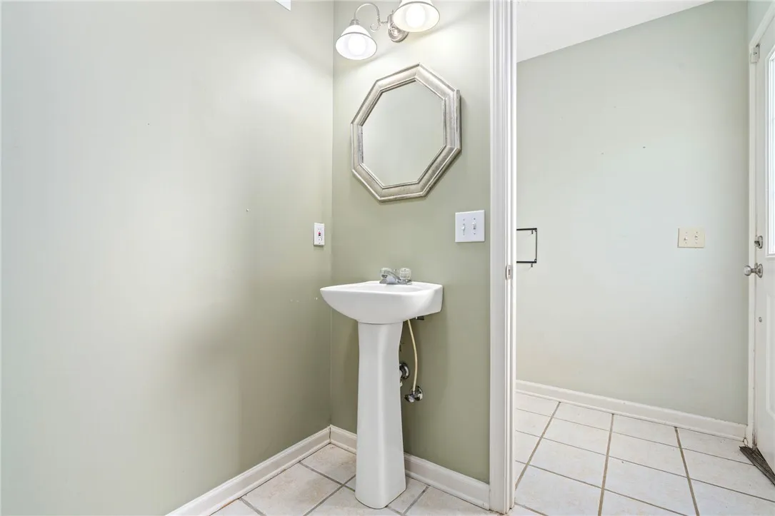 A compact half bath with a classic pedestal sink and ample vanity lighting.