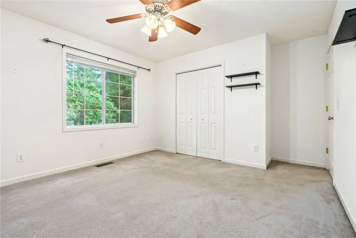 A quiet retreat with a garden view, this bedroom features carpet flooring and a ceiling fan.